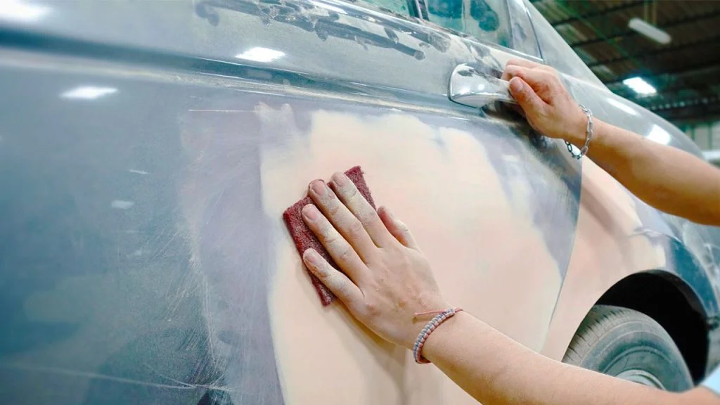 close up of a man sanding a car getting it ready to paint